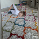 Boy with hearing loss laying on a fuzzy carpet