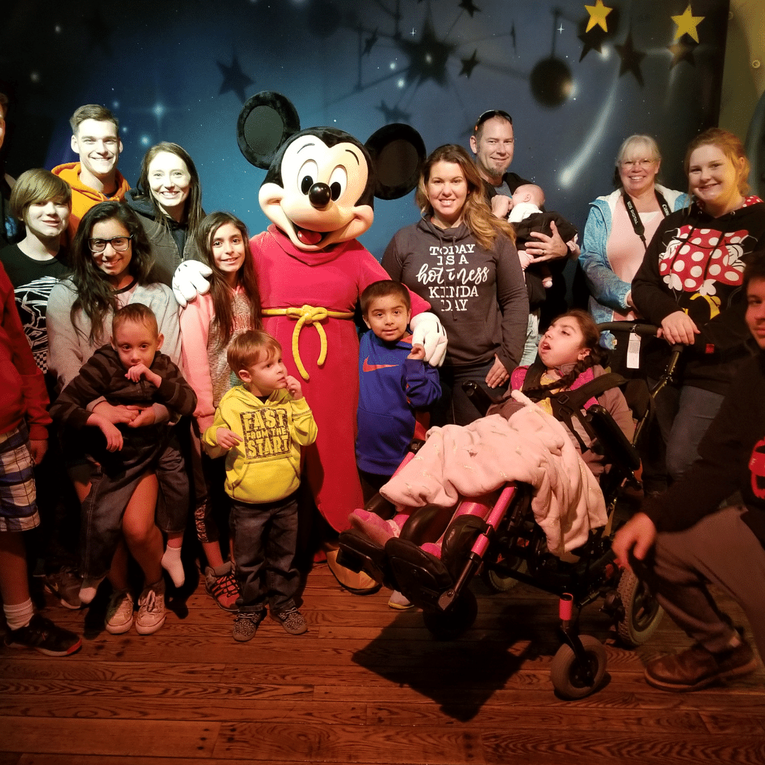 Girl in wheelchair with Mickey Mouse and her family