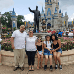 Family smiling in front of Cinderella's Castle at Disney World